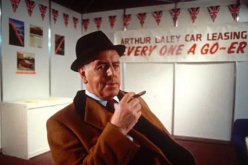 A picture of a car salesman smoking a cigar